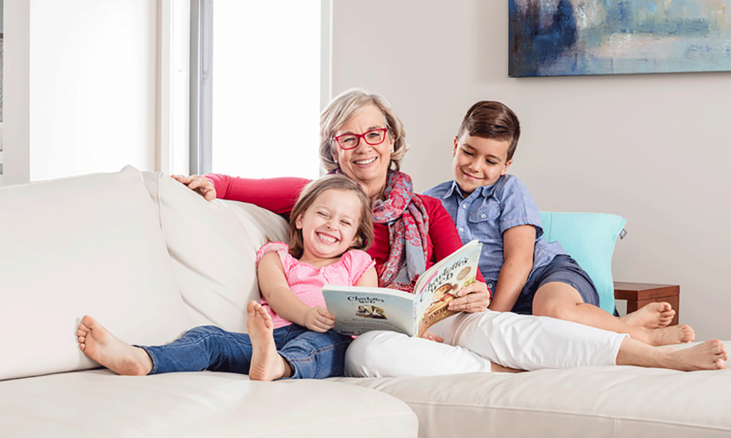 Grandmother wearing glasses reading a book for the children