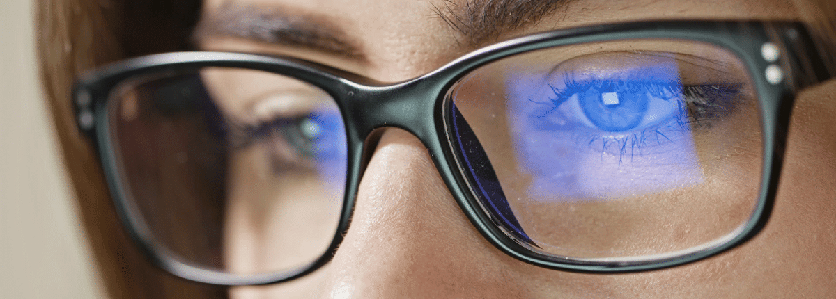 Female model wearing glasses looking at blue light screen