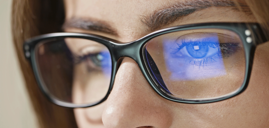 Female model wearing glasses looking at blue light screen