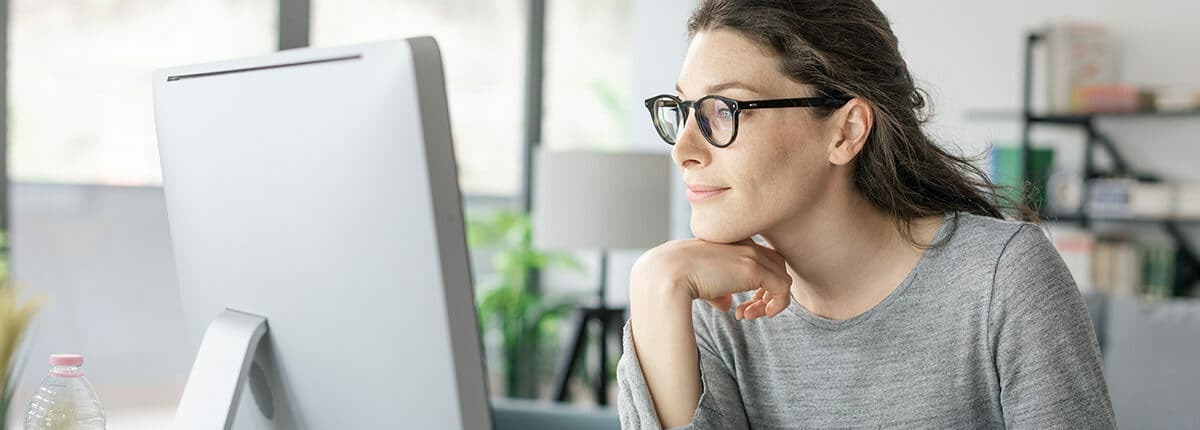 woman with glasses looking at computer